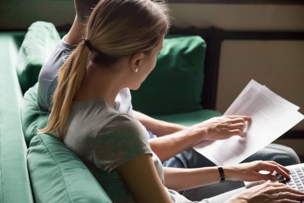 Kvinna och man i soffa med en faktura framför en dator