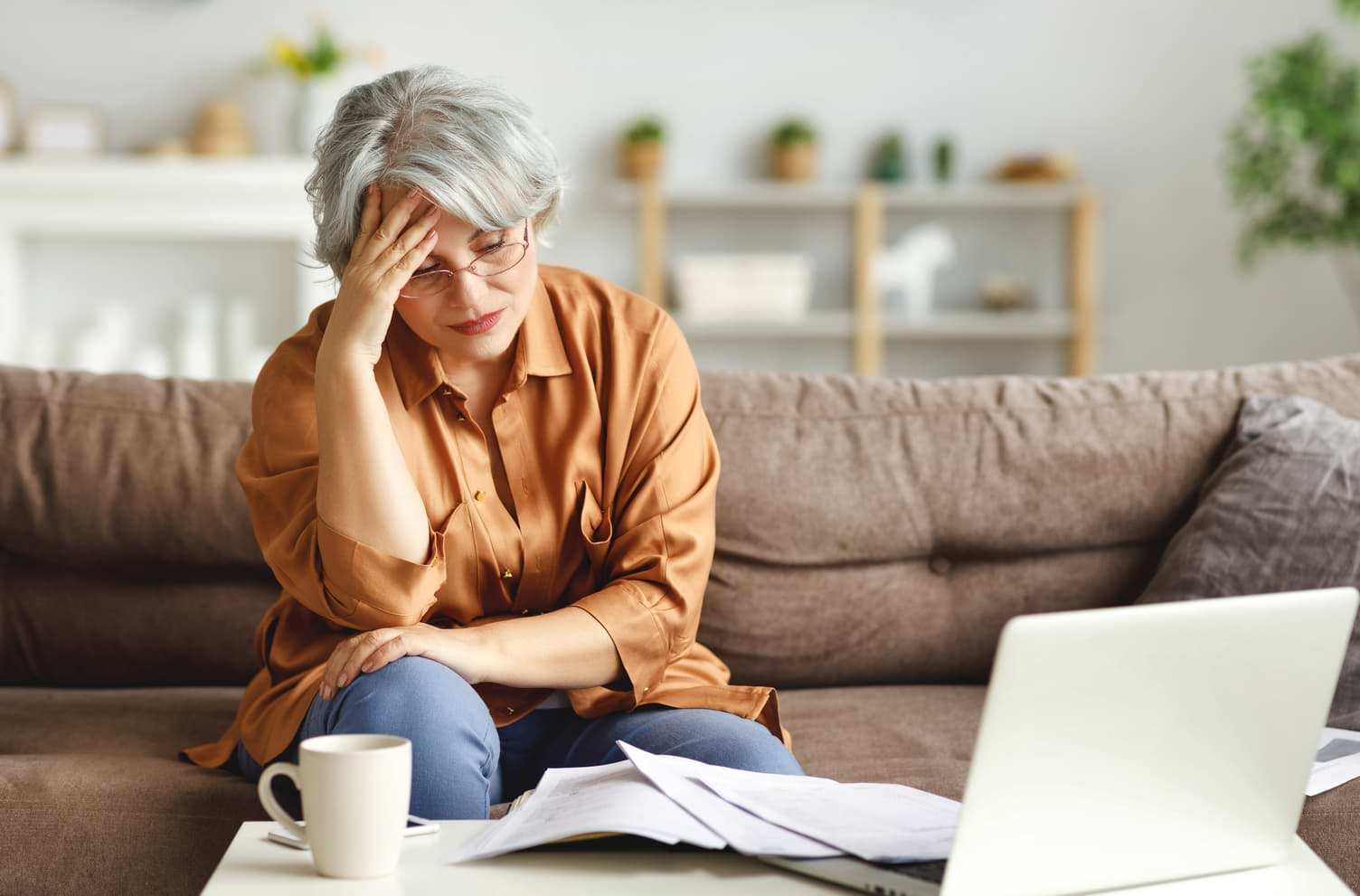 Stressad kvinna vid dator med räkningar