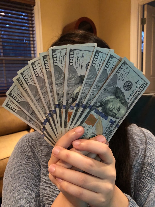 En kvinna som håller i en stor bunt med 100-dollarsedlar.